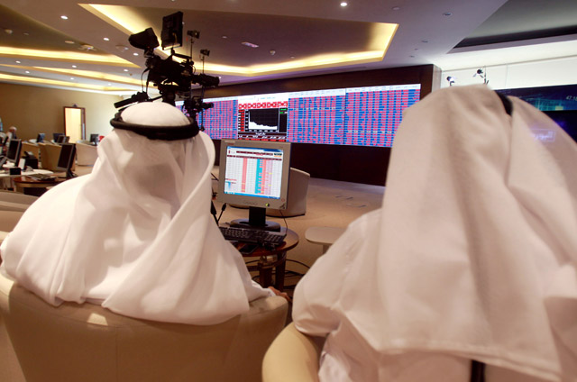 Traders monitor screens displaying stock information at Qatar Stock Exchange in Doha, Qatar, on Monday (Reuters file photo)