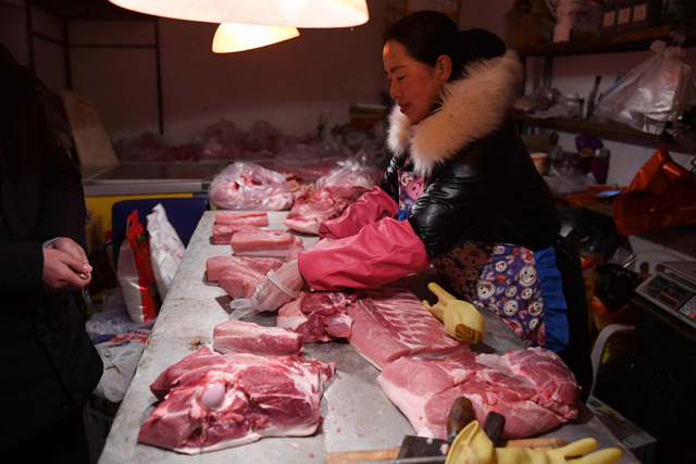 This file photo taken on January 8, 2020 shows a butcher preparing pork for a customer in Datai village, west of Beijing  (AFP photo)