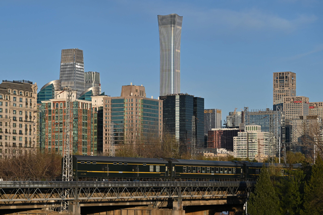A train passes before buildings including the CITIC Tower (top C) in Beijing on Tuesday (AFP photo)