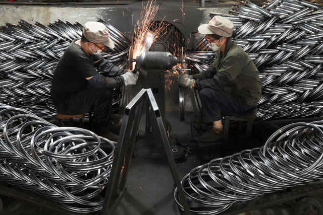 Workers polish bicycle wheels at a factory which produces bicycle parts for export in Hangzhou, in China's eastern Zhejiang province on Monday (AFP photo)