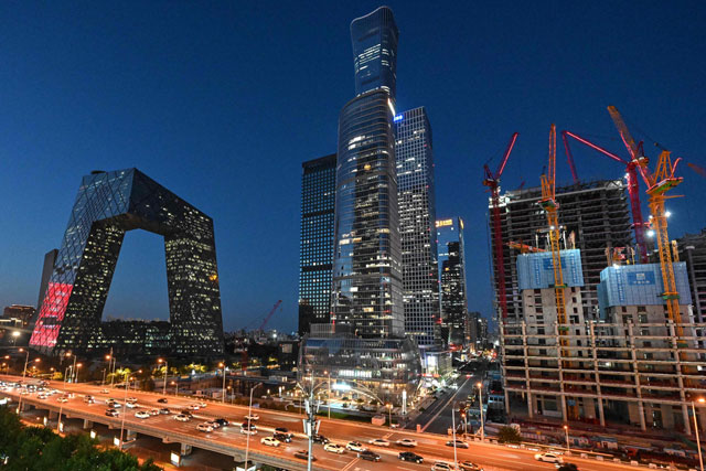 Vehicles move past illuminated CCTV tower and other skyscrapers in Beijing on Thursday (AFP photo)