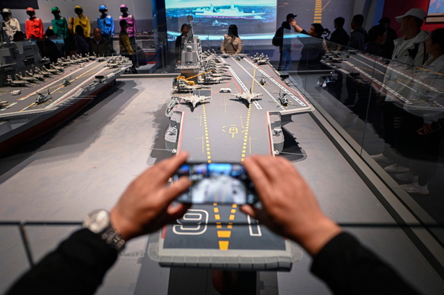This picture taken during a media tour organised by the Chinese People’s Liberation Army Navy (PLAN) to mark its 75th founding anniversary, shows a man taking pictures of a model of the Chinese Navy Liaoning aircraft carrier at the PLA Naval Museum in Qingdao, China’s Shandong province on April 23, 2024 (AFP file photo)