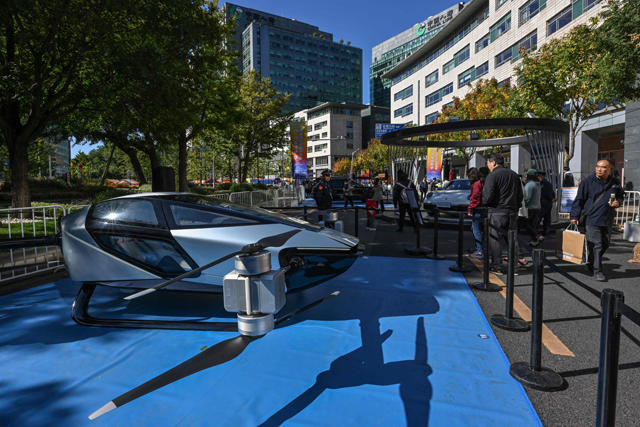 Visitors walk past the Traveler X2 developed and produced by Xiaopeng Huitian during a car festival in Beijing on Saturday (AFP photo)