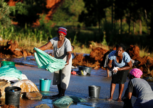 Women wash clothes in a river of water running across a road that was created after Cyclone Idai in Chimanimani, Zimbabwe, on Sunday  (Reuters photo)