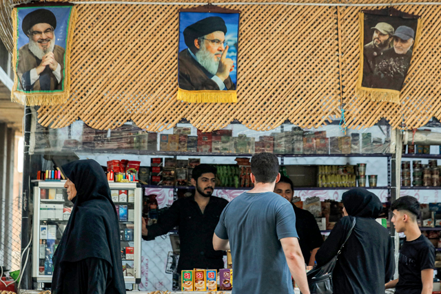 Pictures of Hassan Nasrallah (L and C), the late leader of the Lebanese Shiite group Hezbollah who was killed in an Israeli air strike in Beirut days earlier, hang above a stall as people shop in Damascus' Sayyida Zeinab district on September 29 (AFP photo)