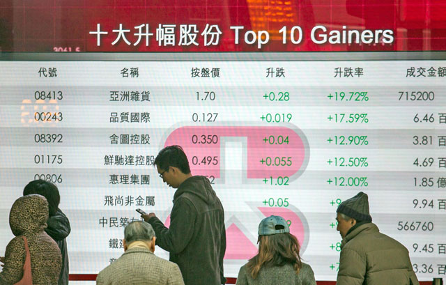 Pedestrians walk past a board displaying the top gainers on the Hang Seng Index at a bank in Hong Kong on Tuesday (AFP photo)