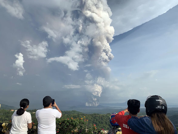 People take photos of a phreatic explosion from the Taal volcano as seen from the town of Tagaytay in Cavite province, southwest of Manila, on Sunday (AFP photo)