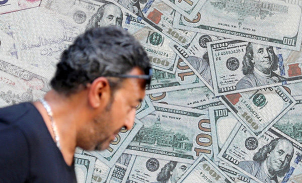 A man walks past an exchange bureau advertisement showing images of the US dollar in Cairo, Egypt, on Wednesday (Reuters photo)