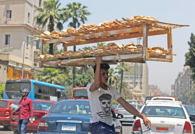 A man rides a bicycle as he carries bread on his head along a busy street in Cairo, Egypt, on Wednesday (Reuters photo)