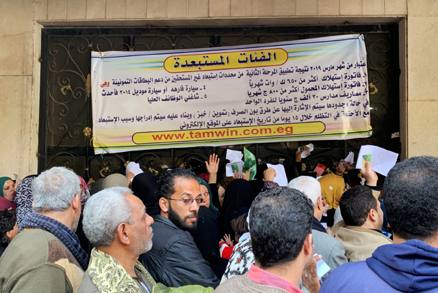 Egyptians crowd to submit petitions to remain on the state's food subsidy programme, under a sign showing the new rules for exclusion in central Cairo, Egypt, on Thursday (Reuters photo)