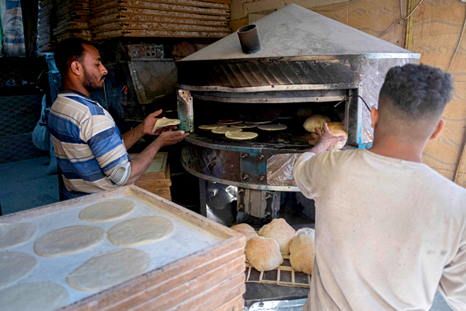 This photo shows an Egyptian man while he is baking bread at a market in Cairo, on Thursday (AFP photo)