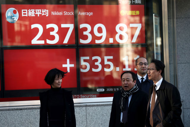 People wait to cross a street in front of a stock indicator displaying share prices of the Tokyo Stock Exchange in Tokyo, on Thursday (AFP photo)