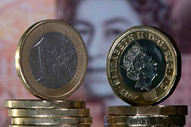 British one pound sterling coins and one Euro coins are arranged in front of a British ten pound sterling note for a photo in London, on December 14, 2017 (AFP photo)