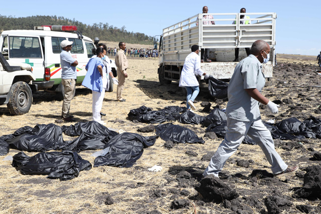 A rescue team walks past collected bodies in bags at the crash site of Ethiopia Airlines, near Bishoftu, a town some 60km southeast of Addis Ababa, Ethiopia, on Sunday (AFP photo)