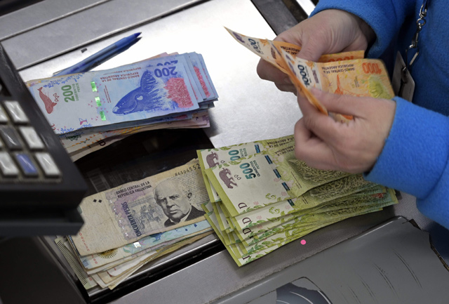 A cashier counts Argentine pesos bills at a supermarket in Buenos Aires on Thursday (AFP photo)