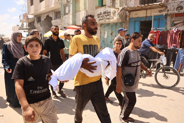 A Palestinian man carries a body during a funeral after an Israeli strike on a school housing displaced Palestinians in Gaza City's Zaytoun neighbourhood on Saturday. (AFP photo) t