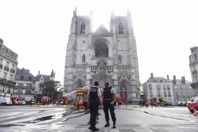 French Police officers stand ready as firefighters are at work to put out a fire at the Saint-Pierre-et-Saint-Paul cathedral in Nantes, western France, on Saturday  (AFP photo)