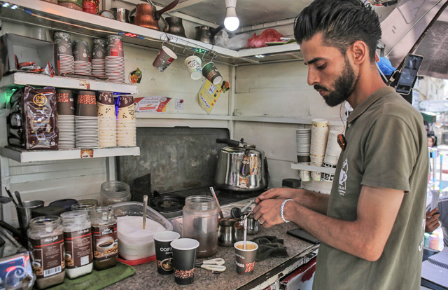 Shaaban Hamuda, 31, a Palestinian business management graduate, makes coffee to be delivered to customers, inside his small stand near Rafah Market, in the southern Gaza Strip, on July 13 (AFP photo)