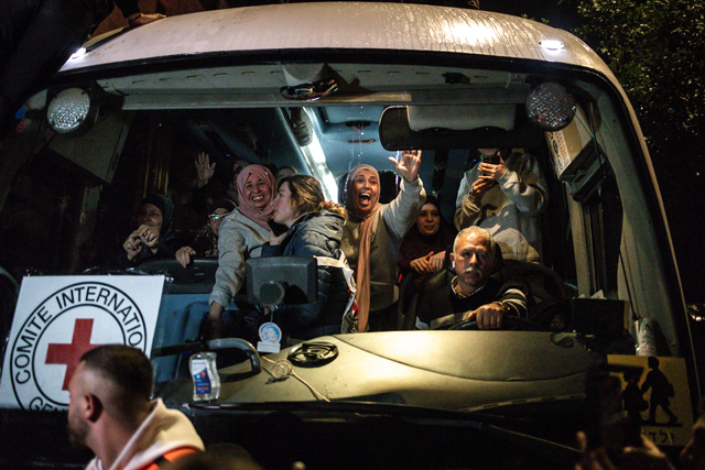 Palestinian freed prisoners’ wave to the crowd from a Red Cross bus that drove them out of the Israeli Ofer military prison in the occupied West Bank, as they arrive in Beitunia (AFP photo)
