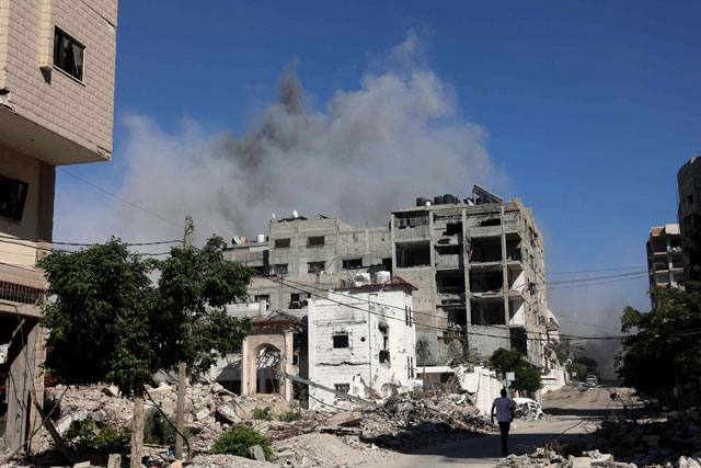 A Palestinian man walks along a road past damaged buildings during the Israeli military bombardment of Gaza City on Sunday (AFP photo)