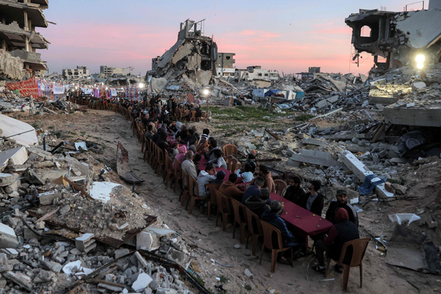 People gather by the rubble of destroyed buildings for a mass gathering for a communal Iftar fast-breaking meal on the second day of the Muslim holy month of Ramadan in the area of Al Dahduh in Gaza City's Tal Al Hawa district on Sunday (AFP photo)