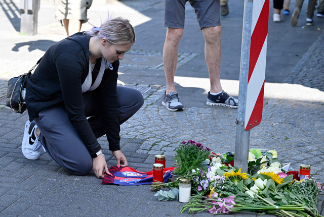A woman kneels at a makeshift memorial of flowers and candles for the victims on August 24, 2024 close to the scene where at least three people were killed and several injured (AFP photo)