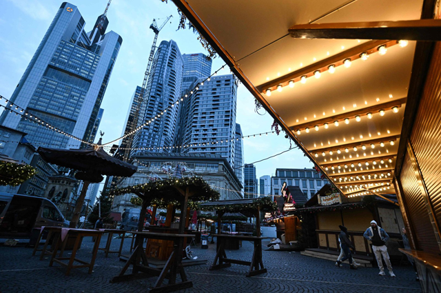 People walk through Christmas-themed booths in front of banking district skyline, central Frankfurt, Germany, Nov. 21, 2024  (AFP file photo)