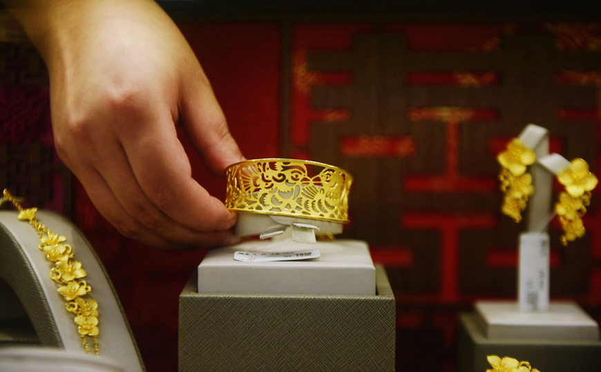 A staff member places gold jewellery in a display at a store in Hangzhou, in China's eastern Zhejiang province, on Monday  (AFP photo)