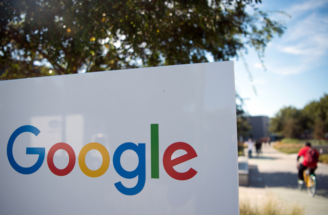 The photo taken on November 4, 2016, shows a man riding a bike past a Google sign and logo at the Googleplex in Menlo Park, California (AFP photo)