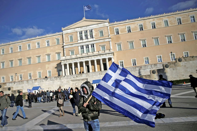 A farmer waves a Greek national flag in front of the parliament building during a demonstration to demand tax reductions and compensation in Athens, Greece, on Tuesday (Reuters photo)