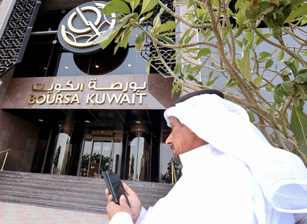 A Kuwaiti trader checks his phone at the entrance of the Boursa Kuwait financial market in Kuwait City on Sunday (AFP photo)