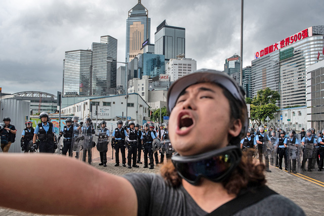 A protester shouts in front of police outside the government headquarters after the annual flag raising ceremony to mark the 22nd anniversary of the city's handover from Britain to China, in Hong Kong, on Monday (AFP photo)