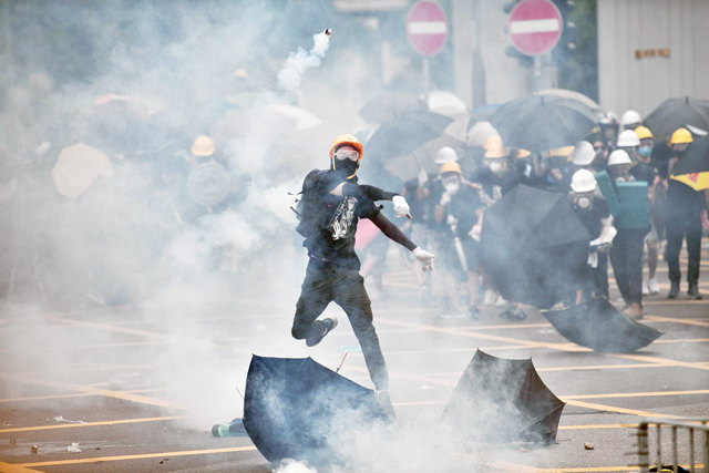 A protester throws tear gas back at police officers during a demonstration in the district of Yuen Long, in Hong Kong, on Saturday (AFP photo)