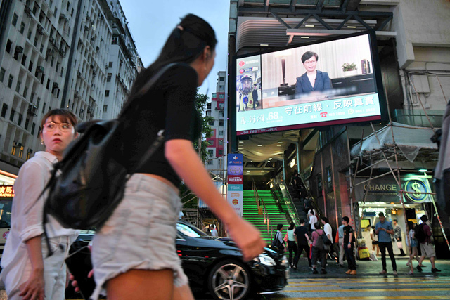 Pedestrians walk past a large monitor display showing a news broadcast of Hong Kong Chief Executive Carrie Lam announcing she will permanently shelve a controversial extradition bill in Hong Kong on Wednesday (AFP photo)