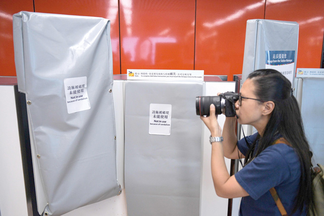 A woman takes photographs during a media tour of the closed Mong Kok MTR train station in Hong Kong on Tuesday  (AFP photo)