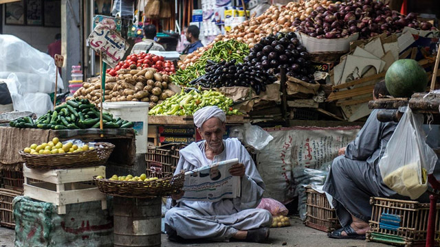 An Egyptian vendor reads the newspaper outside his fruit and vegetables stand in Cairo on Saturday (AFP photo)