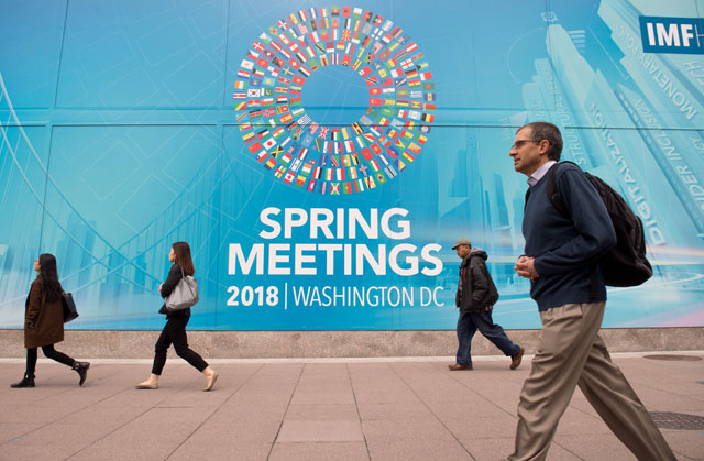 People walk past the IMF headquarters building during the 2018 Spring meetings of the IMF and World Bank Group in Washington, DC, on Tuesday (AFP photo)