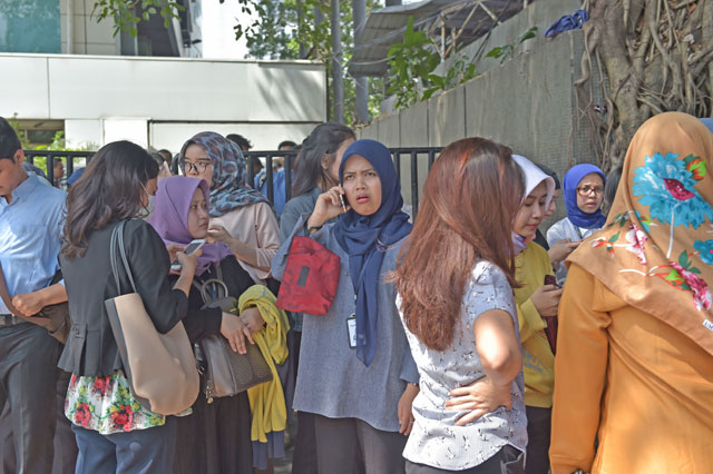 Indonesians wait outside an office building after a 6.4 magnitude quake hit Jakarta on Tuesday (AFP photo)