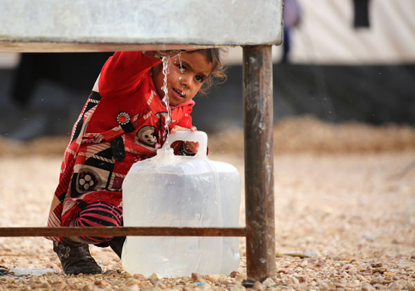 An Iraqi refugee girl, who fled the Iraqi city of Mosul due to the fighting between government forces' and Daesh militants, fills a container with water at the UN-run Al Hol Refugee Camp in Syria's Hasakeh province, on Monday (AFP photo)