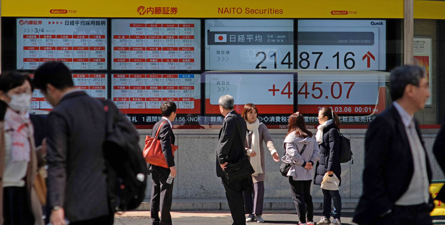 Pedestrians walk past at an electronics stock indicator showing a share prices of the Tokyo Stock Exchange in Tokyo on Tuesday (AFP photo)