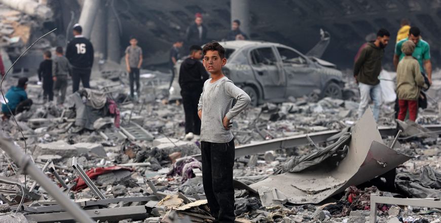 A young boy looks on as Palestinians stand amid the devastation in the yard of a school, a day after it was hit by an Israeli strike, in the Al Tuffah neighbourhood of Gaza City on Friday (AFP photo)