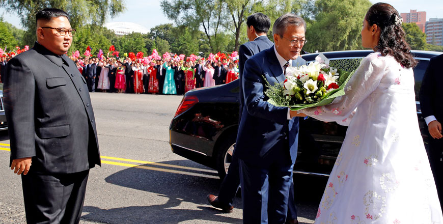 South Korean President Moon Jae-in holds flowers as North Korean leader Kim Jong-un looks on, during a car parade in Pyongyang, North Korea, on Tuesday (Reuters photo)