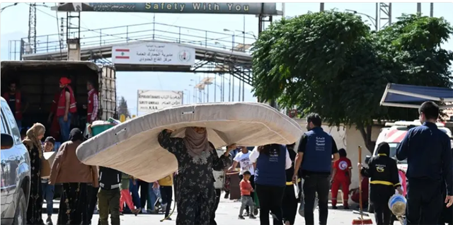 A woman carries a mattress over her head as she enters Syria from Lebanon via the Jusiyeh border crossing with Quseir in Syria's central Homs province on October 2, 2024 (AFP photo)