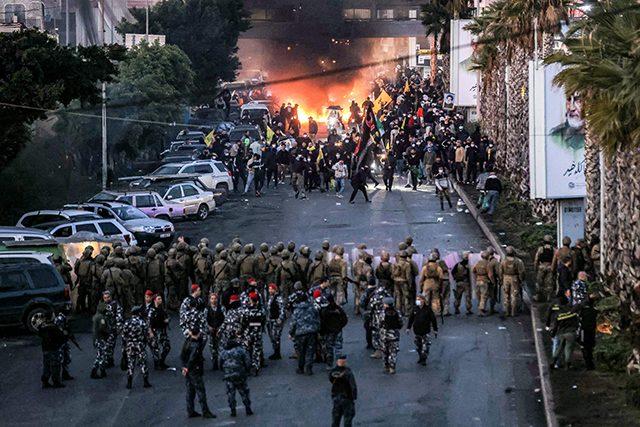 Fire from burning tires burns as supporters of Lebanese Shiite Islamist movement Hizbollah stand before Lebanese Army soldiers to block the road to Beirut International Airport over yesterday (AFP photo)