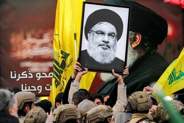 A protester holds a framed portrait of Hassan Nasrallah, the slain leader of the Lebanese Shiite Islamist movement Hizbollah, before Lebanese army soldiers in Beirut on Saturday (AFP photo)
