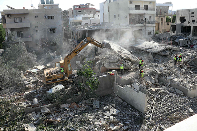 Rescuers with the Amal-linked Risala Scouts association use an excavator to search the rubble for survivors or victims, a day after an Israeli air strike hit their headquarters in the southern Lebanese village of Deir Qanoun, reportedly killing at least six , on Sunday (AFP photo)