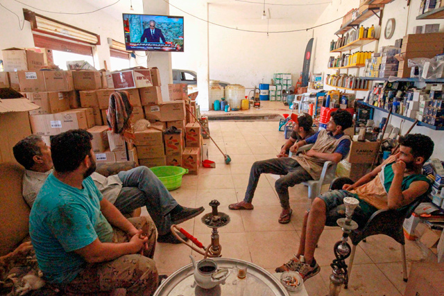 Libyan mechanics watch a televised speech by Khalifa Haftar, during the talks dubbed the ‘Cairo declaration’ at their shop in Benghazi, on Saturday  (AFP photo)