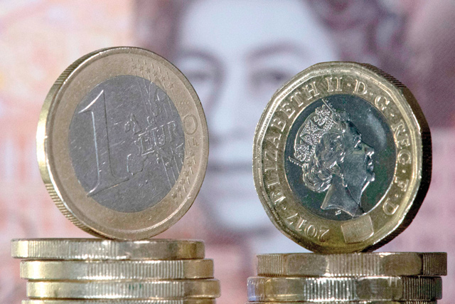In this photo, taken on December 14, 2017, British one pound sterling coins and one Euro coins are arranged in front of a British ten pound sterling note for a photograph in London (AFP file photo)