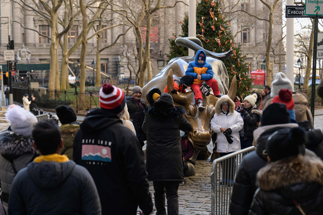 Visitors gather around the Charging Bull statue on Tuesday in New York City (AFP photo)