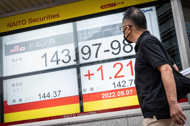 In this photo, a man walks past an electronic board showing the rate of the Japanese yen against the US dollar, in a business district of Tokyo, on Monday (AFP photo)